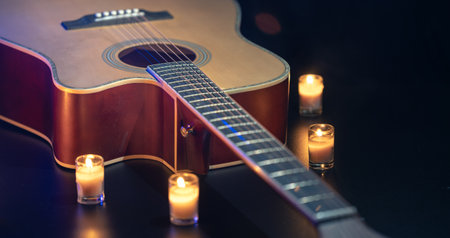 Acoustic guitar on a black background with candles.の写真素材