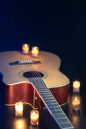 Acoustic guitar on a black background with candles.の写真素材