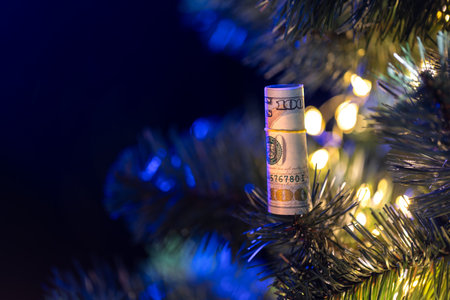 Dollar bill hanging on Christmas tree with bokeh lights.の写真素材