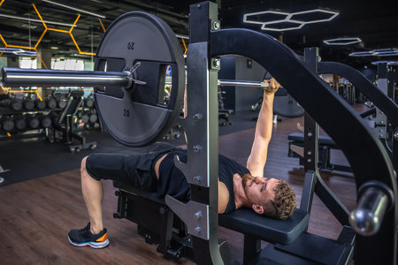 An athlete in the gym swings triceps with a barbell. Sports lifestyle.の写真素材