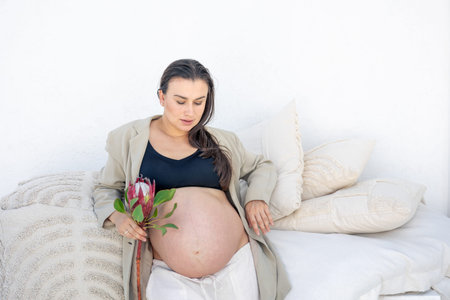 Beautiful stylish pregnant woman with protea flower. Pregnancy concept.