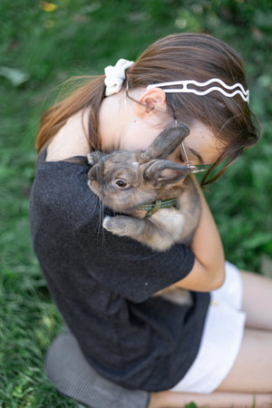 A girl plays with a domestic rabbit on the street. Pet concept.の写真素材