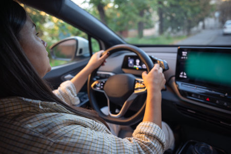 Young woman driving a car. Hands on the wheel. View from the back to the road.