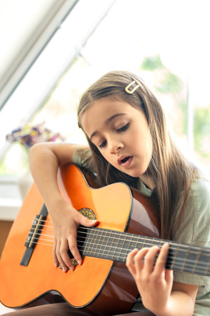 A cute girl plays the guitar. A little girl with a guitar.の写真素材