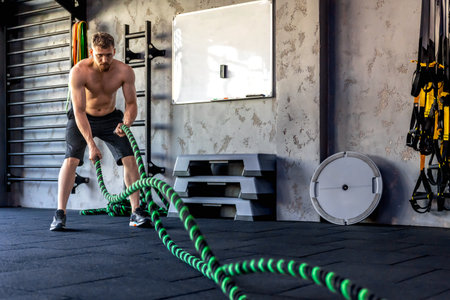 Ahlete performs triceps exercises with cross fit rope. Sports lifestyle.の写真素材