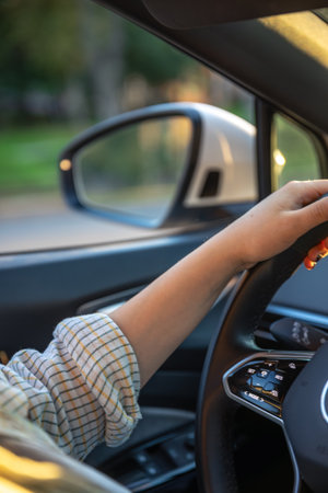 Young woman driving a car. Hands on the wheel. Side mirror in the car.の写真素材