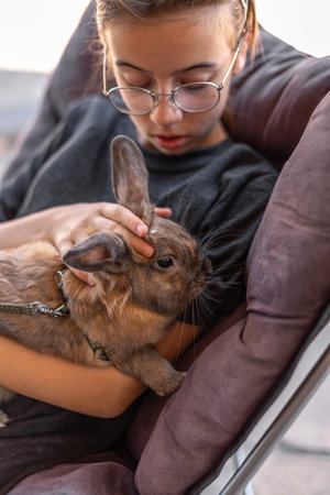 A girl plays with a domestic rabbit on the street. Pet concept.の写真素材