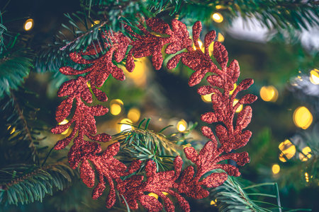 Decorative red wreath on a Christmas tree with bokeh lights.の写真素材