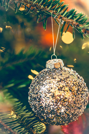 Silver shiny Christmas ball on a Christmas tree branch, close-up.の写真素材