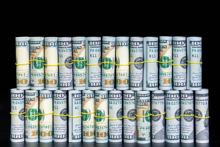 Twisted 100 dollar bills on a black background. Finance concept background.
