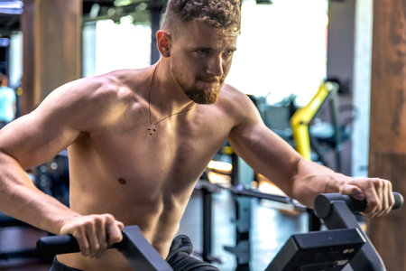 Athlete doing exercises on an air bike exercise bike close-up.