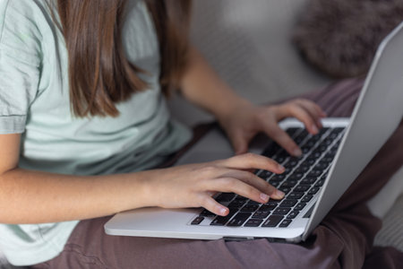 The girl is typing on the laptop keyboard. Girls hands on the keyboard.の写真素材