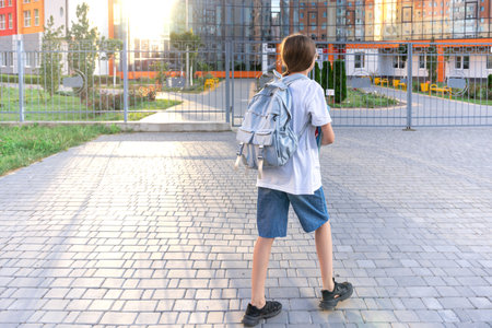 Schoolgirl with a backpack on her shoulders. School on the background of the sunset. Back to school.の写真素材