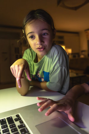 Beautiful girl studies at the computer at night. Technology and education.