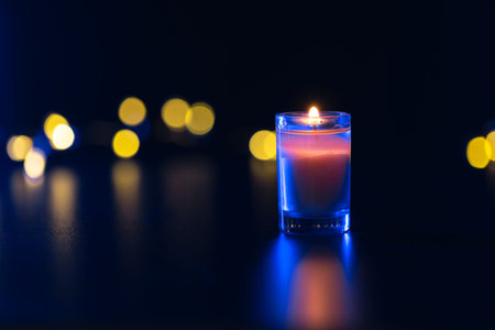 Burning candle on black background with bokeh. Memorial Day.