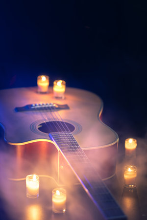 Acoustic guitar on a black background with candles.の写真素材