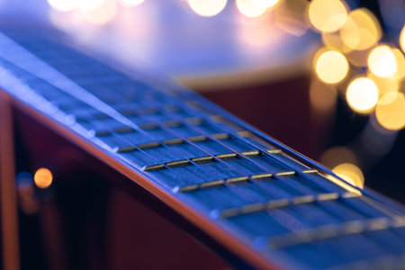 Part of an acoustic guitar, guitar fretboard on a black background.