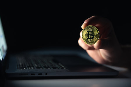 Bitcoin coin near laptop on black background. Finance and crypto money concept.の写真素材