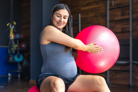 Pregnant sports woman with fit ball in the gym. The concept of sports lifestyle.の写真素材