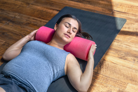 Pregnant woman in the gym on a mat with a massage roller.の写真素材