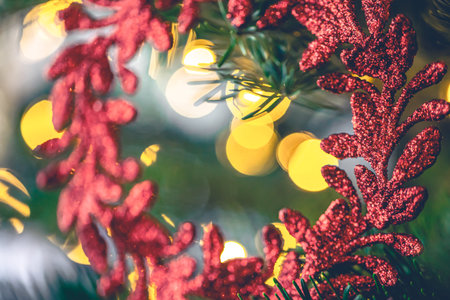 Decorative red wreath on a Christmas tree with bokeh lights.の写真素材