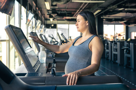 Pregnant woman on a treadmill in the gym. Healthy sports lifestyle.の写真素材