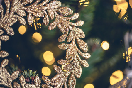 Decorative golden wreath on a Christmas tree with bokeh lights.の写真素材