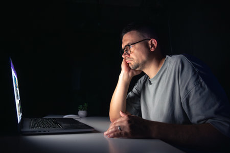Young man works at the computer at night.の写真素材