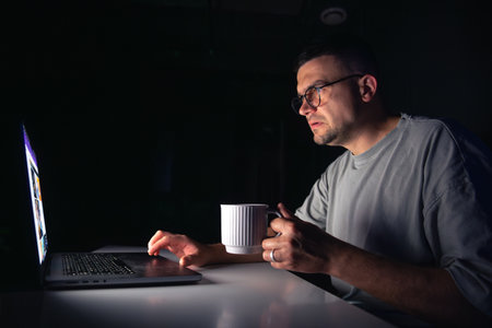 Young man works at the computer at night.の写真素材