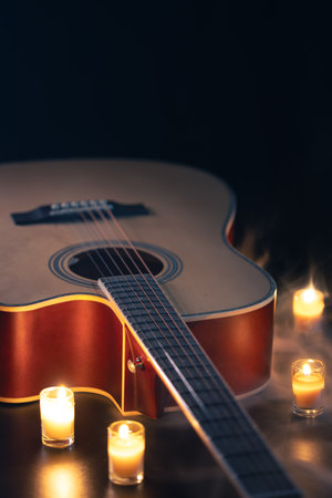 Acoustic guitar on a black background with candles.の写真素材
