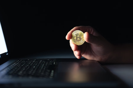 Bitcoin coin near laptop on black background. Finance and crypto money concept.の写真素材