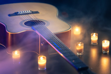 Acoustic guitar on a black background with candles.の写真素材