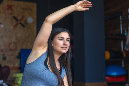 Pregnant woman in the gym doing warm-up. Sitting on a yoga mat.
