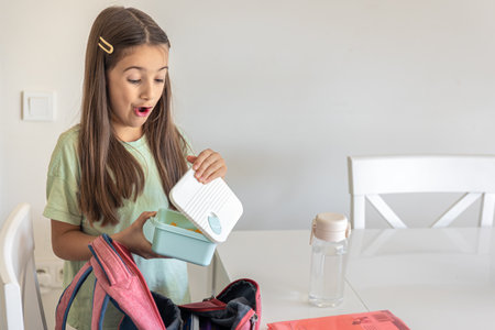 The girl packs a backpack for school. Schoolgirl with a backpack.の写真素材