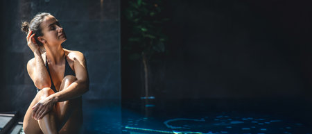 Attractive young woman in a black swimsuit is relaxing in the pool.の写真素材