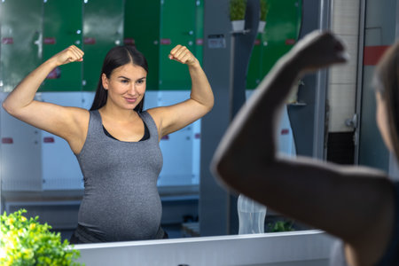 A pregnant woman near a mirror in the gym. A healthy sports lifestyle.の写真素材