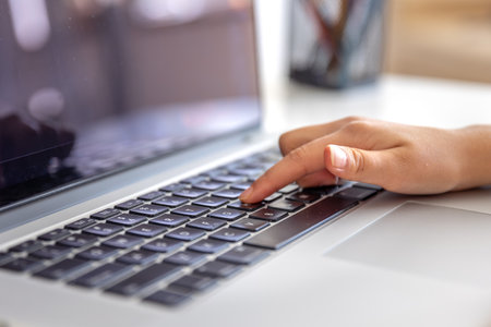 The girl is typing on the laptop keyboard. Girls hands on the keyboard.の写真素材
