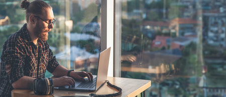 A young man works on a laptop. Remote work using a laptop.