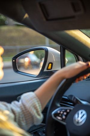 Young woman driving a car. Hands on the wheel. Side mirror in the car.の写真素材