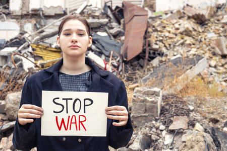 Young woman with message stop war. Woman on the background of ruins.の写真素材