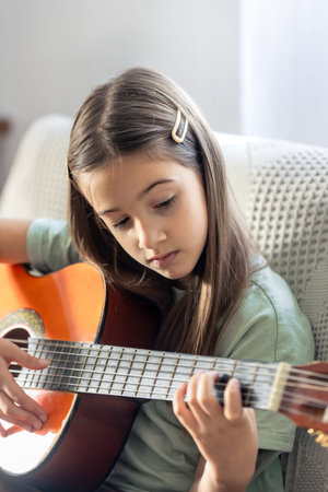 A cute girl plays the guitar. A little girl with a guitar.
