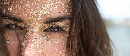 A young woman with sand on her face. Sand on the face.の写真素材