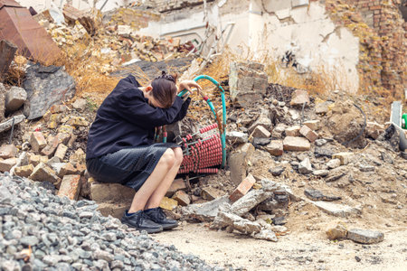 A girl next to a house destroyed by the war. War in Ukraine.の写真素材