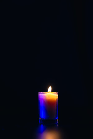 Burning candle on black background with backlight. Memorial Day.の写真素材