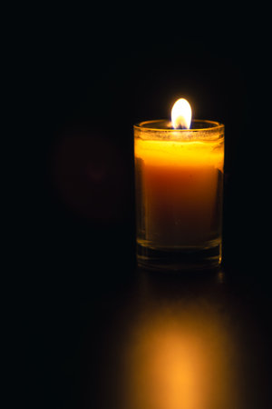 Burning candle on black background with backlight. Memorial Day.の写真素材