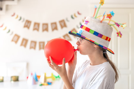A festive girl inflates a balloon on her birthday. Birthday concept.の写真素材