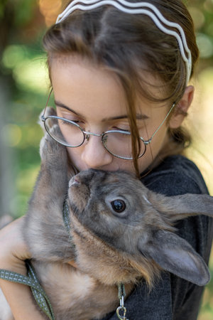 A girl plays with a domestic rabbit on the street. Pet concept.の写真素材