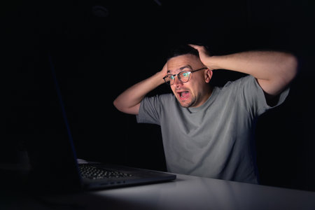 Young man works at the computer at night.の写真素材
