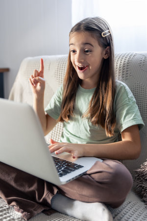A schoolgirl studies online at home. The girl is typing on the laptop keyboard.の写真素材