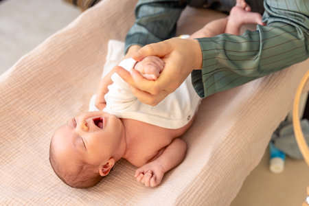 Mother wearing clothes to her baby. Baby healthcare hygiene concept.の写真素材